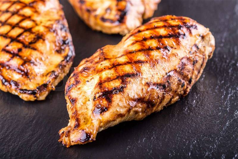 Grilled chicken breast in different variations with cherry tomatoes, mushrooms, herbs, cut lemon on a wooden board or teflon pan. Traditional cuisine. Grill kitchen, stock photo