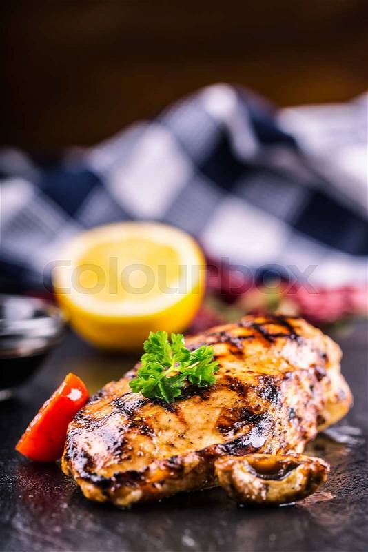 Grilled chicken breast in different variations with cherry tomatoes, \mushrooms, herbs, cut lemon on a wooden board or teflon pan. Traditional cuisine. Grill kitchen, stock photo