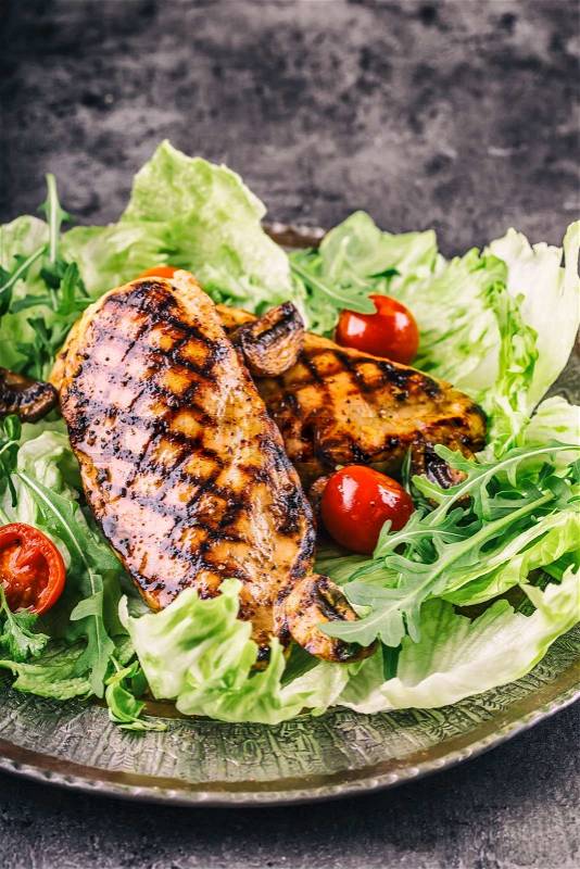 Grilled chicken breast in different variations with lettuce salad cherry tomatoes \mushrooms herbs cut lemon on a wooden board or teflon pan. Traditional cuisine. Grill kitchen, stock photo