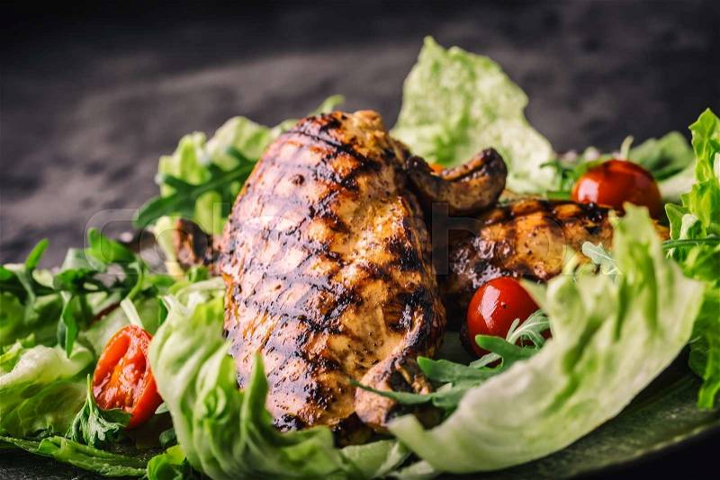 Grilled chicken breast in different variations with lettuce salad cherry tomatoes mushrooms herbs cut lemon on a wooden board or teflon pan. Traditional cuisine. Grill kitchen, stock photo