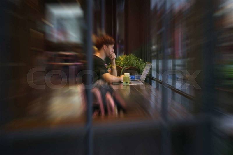 Blurred man use computer in cafe, stock photo