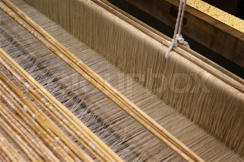 Close up of gold silk weaving on wooden loom, stock photo