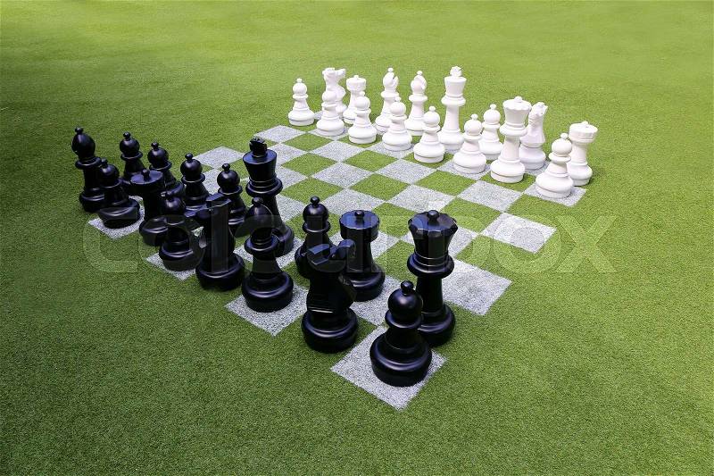 Chessboard and chess pieces on the grass in the garden, stock photo