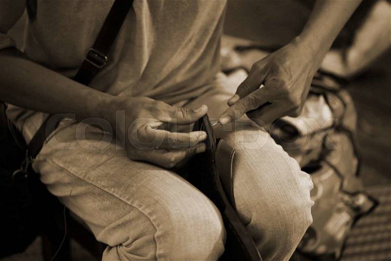 Man hand sewing leather shoe, stock photo