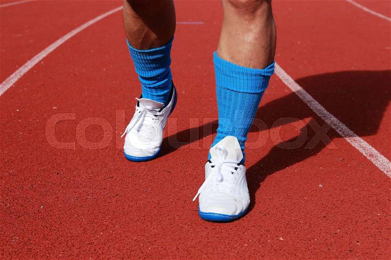 Athletic man running on track in the noon, stock photo