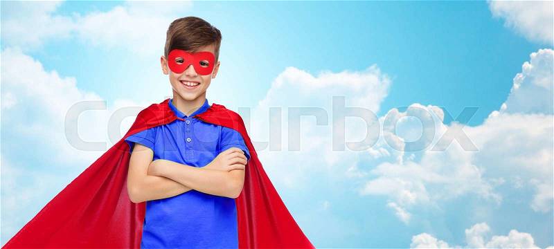 Carnival, childhood, power, gesture and people concept - happy boy in red super hero cape and mask over blue sky and clouds background, stock photo