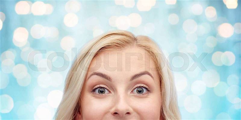 Curiosity, advertisement and people concept - happy young woman or teenage girl face over blue holidays lights background, stock photo