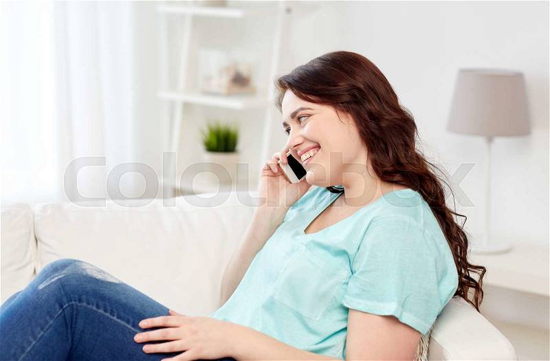 People, technology, communication and leisure concept - happy plus size young woman calling on smartphone at home, stock photo