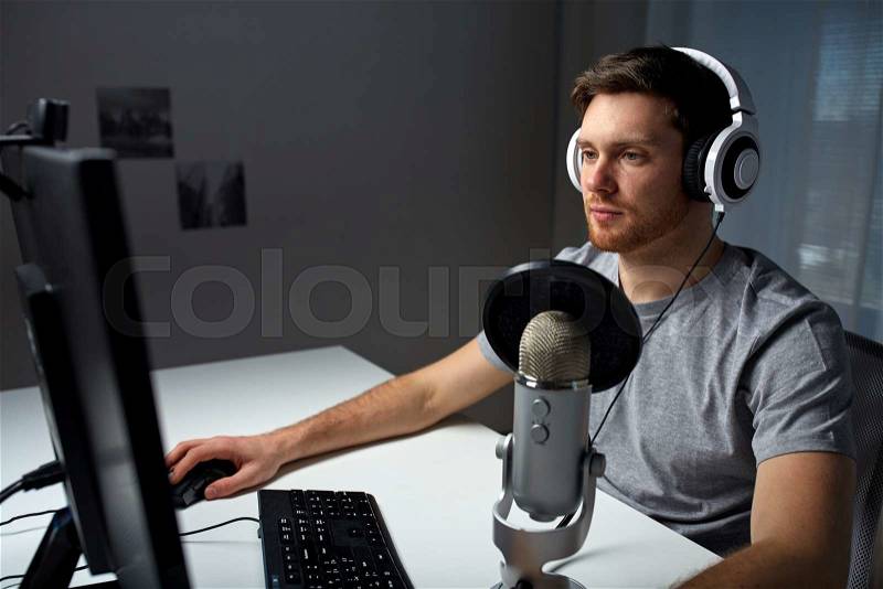 Technology, gaming, entertainment, let\'s play and people concept - young man in headset with pc computer playing game at home and streaming playthrough or walkthrough video, stock photo