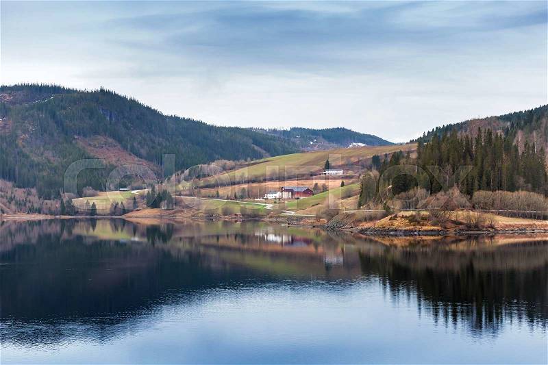Rural Norwegian landscape with still lake water and mountains, stock photo