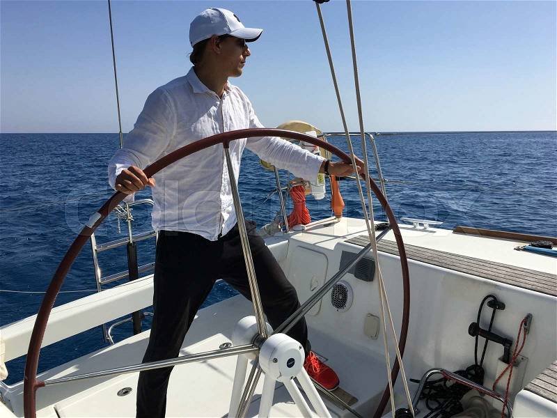 Young man sailing yacht steering wheel vacation sail holidays people travel, stock photo