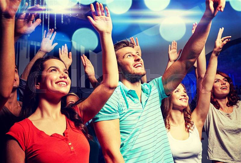 Party, holidays, celebration, nightlife and people concept - smiling friends waving hands at concert in club, stock photo