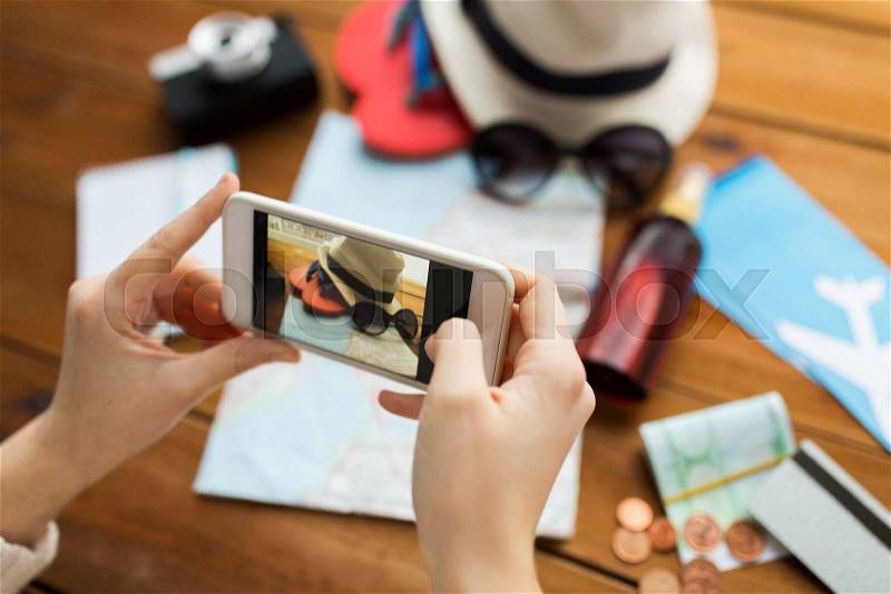 Vacation, tourism, travel, technology and people concept - close up of woman with smartphone photographing map and travel stuff, stock photo