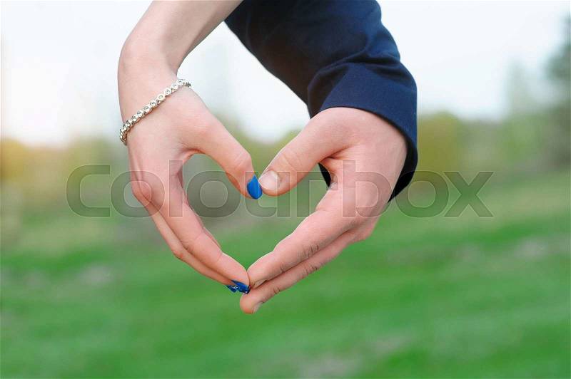Close up of woman and man hands showing heart shape, stock photo