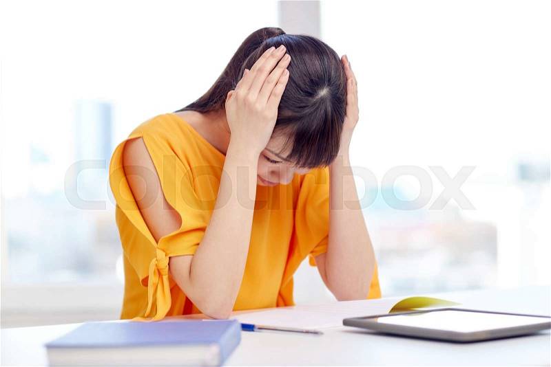 People, education, high school, stress and learning concept - tired asian young woman student with tablet pc computer and notepad suffering from headache at home, stock photo