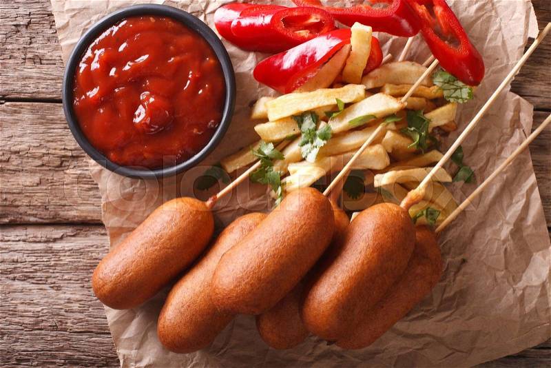 Corn dogs, french fries, pepper and ketchup on the table close-up. Horizontal view from above , stock photo