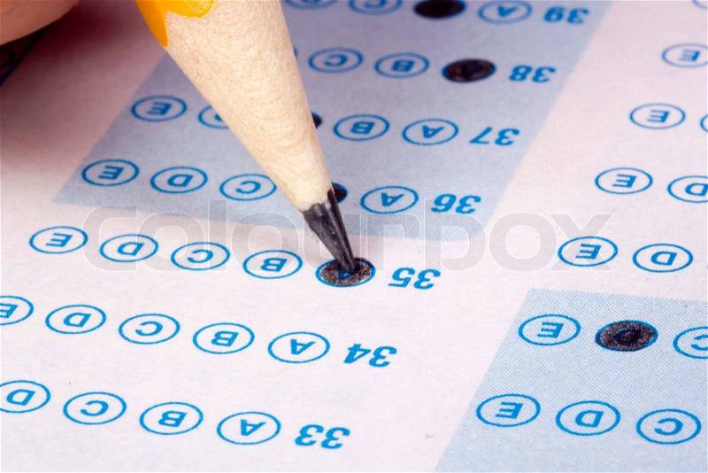 Student filling out answers to a test with a pencil, stock photo