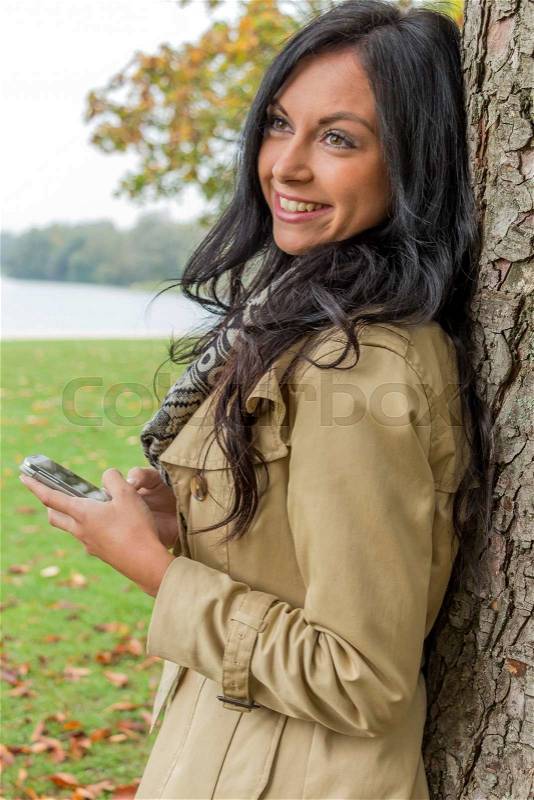 A young woman writes on his mobile phone an sms. communication with a smart phone, stock photo