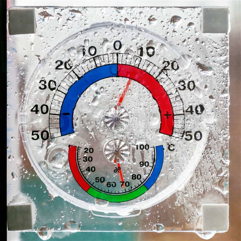 Hygrometer, thermometer all in one behind window in rainy weather, stock photo
