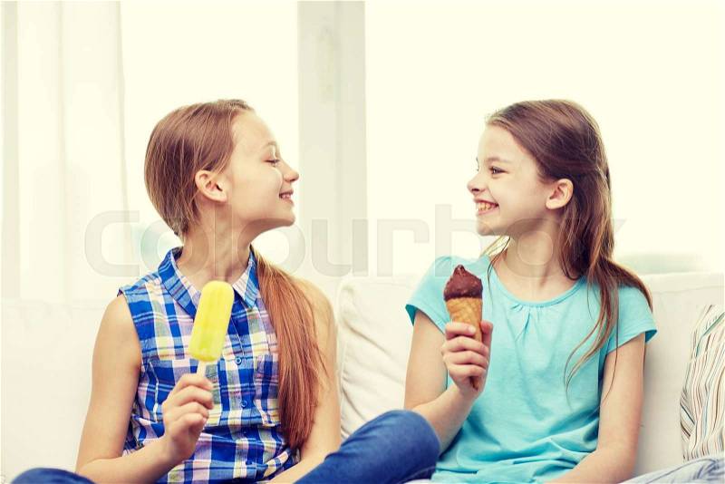 People, children, friends and friendship concept - happy little girls eating ice-cream at home, stock photo