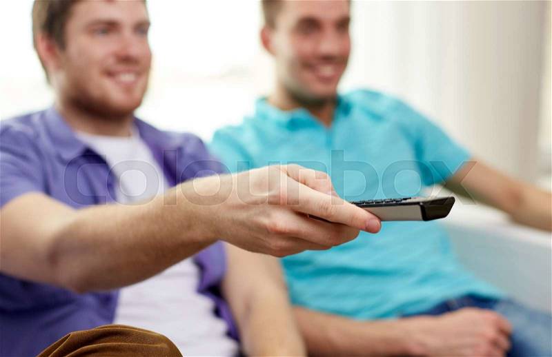 Friendship, sports, people and entertainment concept - close up of happy male friends with remote control watching tv at home, stock photo
