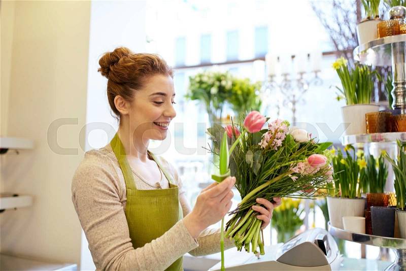 People, business, sale and floristry concept - happy smiling florist woman making bunch at flower shop, stock photo