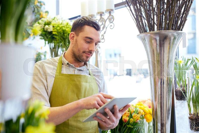 People, business, technology, sale and floristry and concept - happy smiling florist man with tablet pc computer at flower shop, stock photo