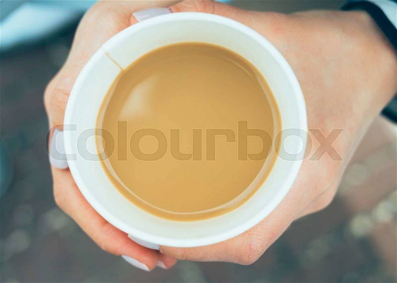 Paper cup of coffee in hand, top view, stock photo