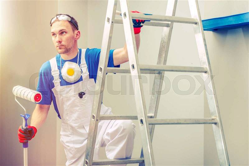 Professional Painting. Professional Painter with Painting Roller on the Ladder. , stock photo