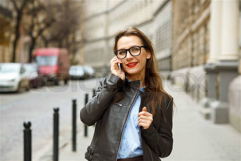 Businesswoman on cellphone walking down the street while talking on smart phone. Happy smiling caucasian business woman busy, stock photo