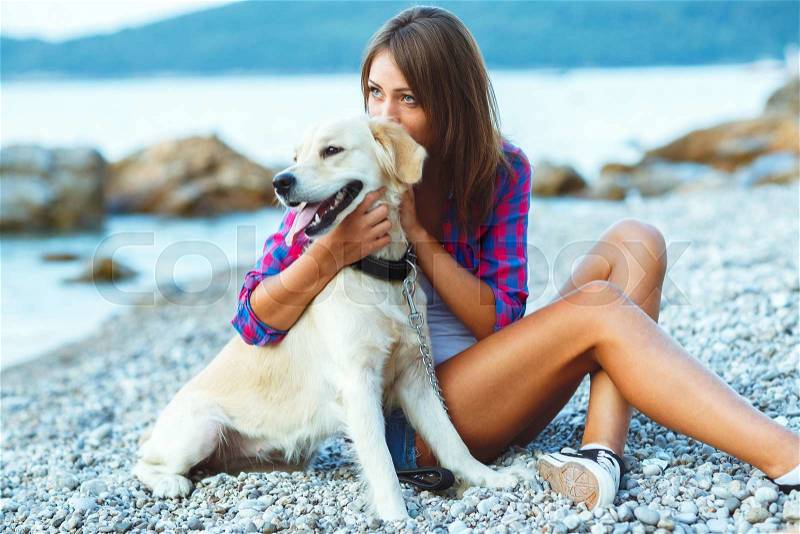 Summer vacation - woman with a dog on a walk on the beach, stock photo
