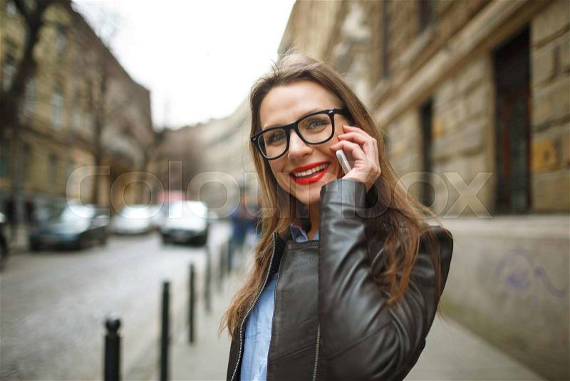 Businesswoman on cellphone walking down the street while talking on smart phone. Happy smiling caucasian business woman busy, stock photo