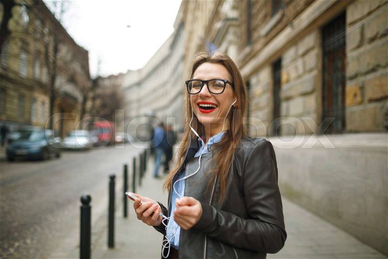 Businesswoman walking down the street while using the smart phone. Happy smiling caucasian business woman busy, stock photo
