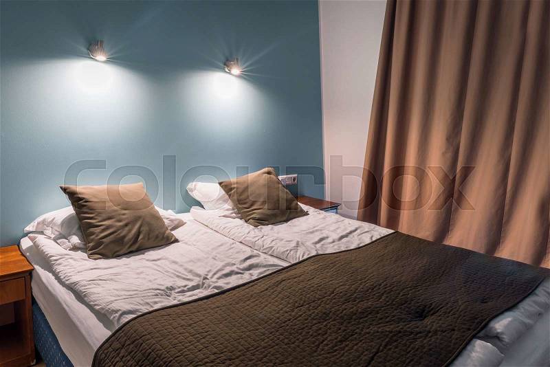 Double bed with pillows and shining lamps, stock photo
