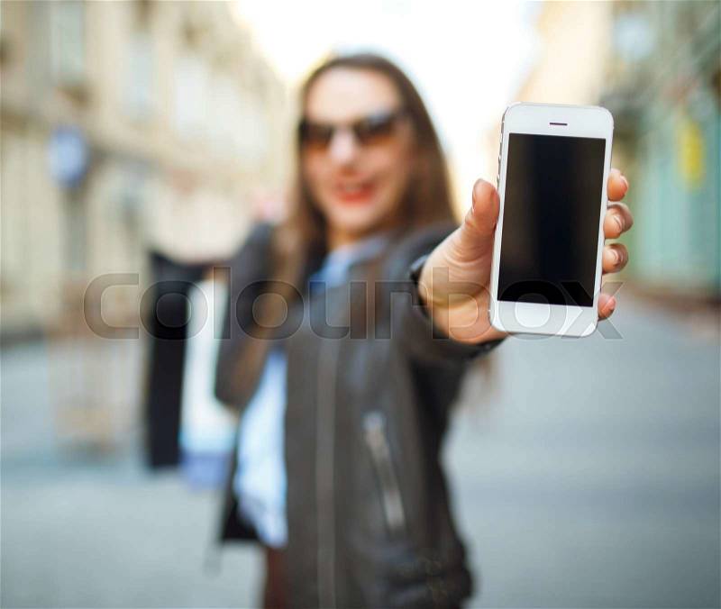 Online shopping concept - beautiful woman with shopping bags and smart phone in the hands on a street, stock photo