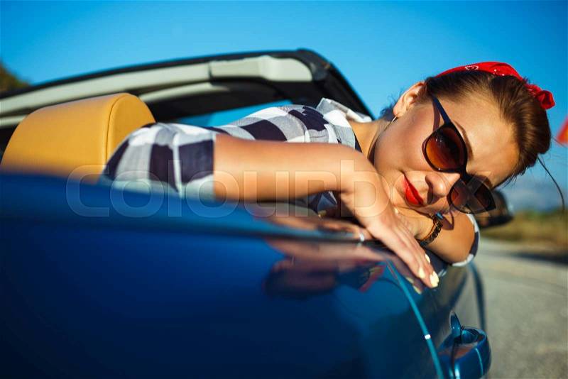 Beautiful pin up woman sitting in cabriolet, enjoying trip on luxury modern car with open roof, fashionable lifestyle concept, stock photo