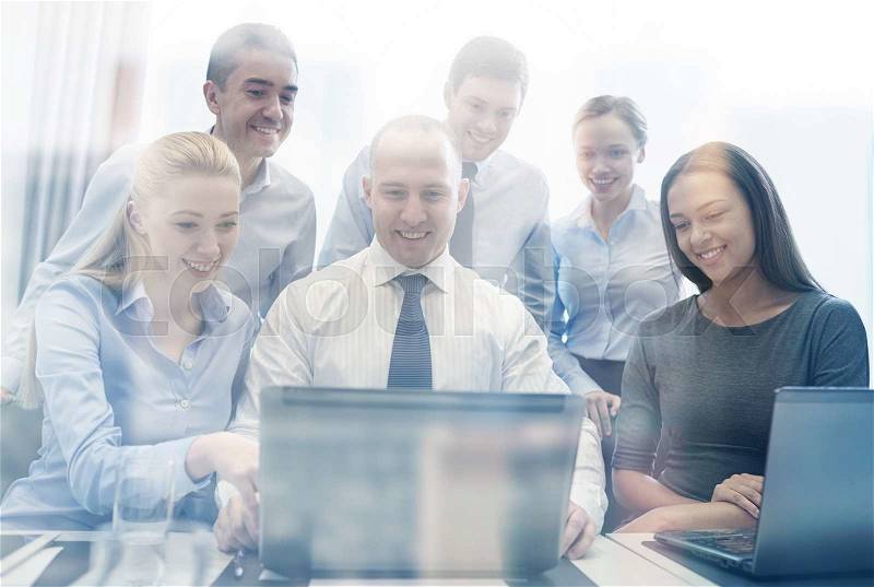 Business, people, technology and communication concept - smiling business team with laptop computer making video conference in office, stock photo