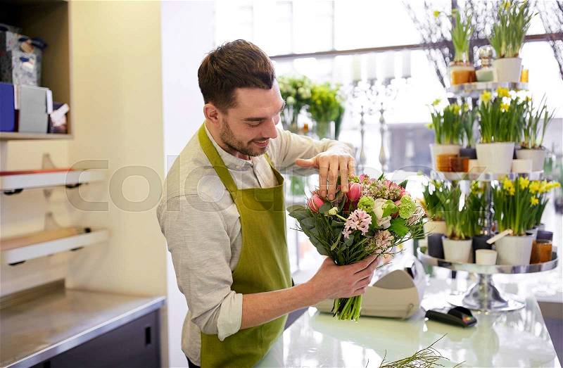 People, business, sale and floristry concept - happy smiling florist man making bunch at flower shop, stock photo