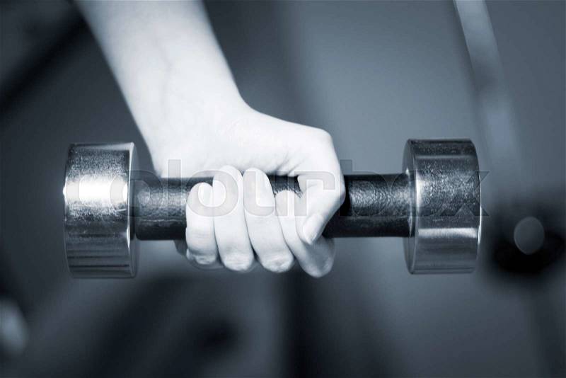 Dumbell weight in hand in fitness gym for weight training, bodybuilding and sports strength training, stock photo