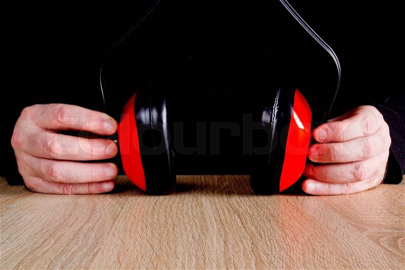 Ear protectors in human hand. On a wooden surface, stock photo