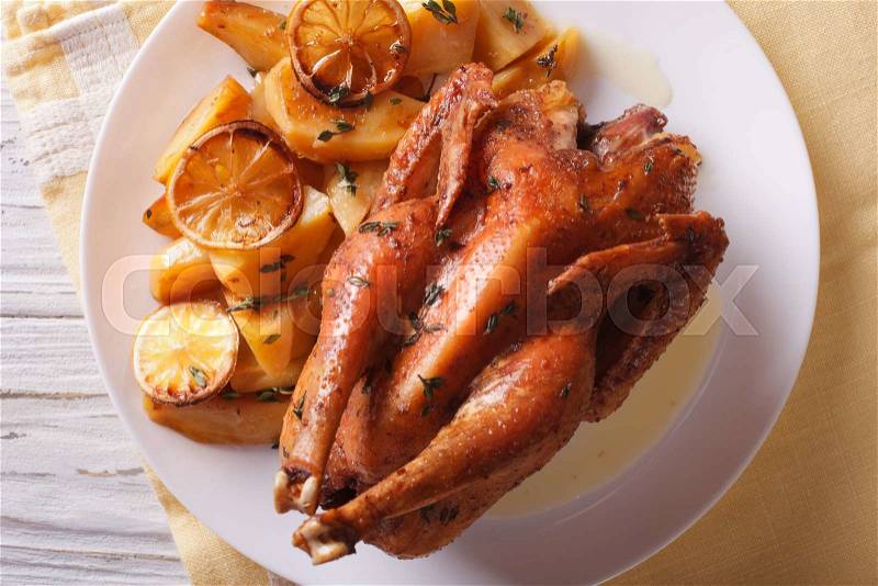 Lemon chicken with potatoes close up on a plate on the table. horizontal view from above , stock photo