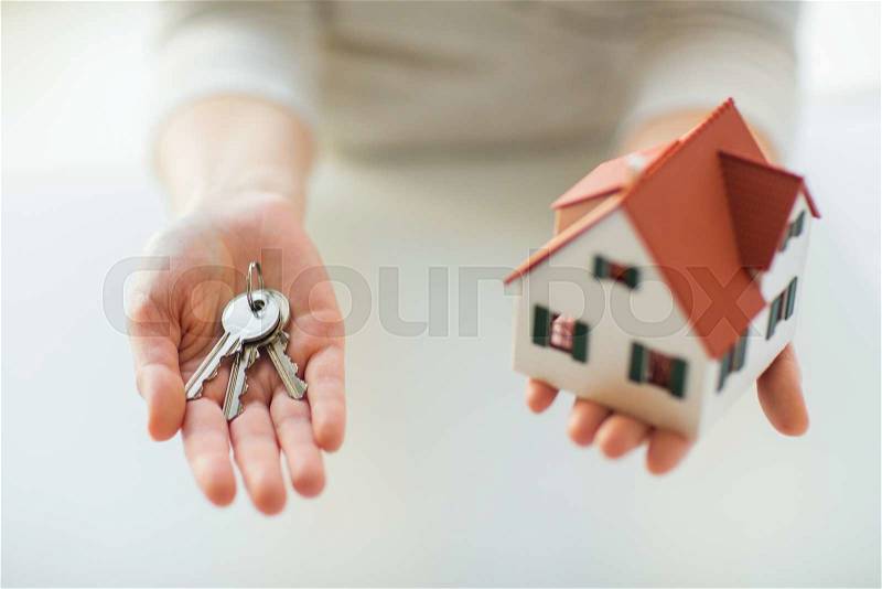 Building, mortgage, real estate and property concept - close up of hands holding house model and home keys, stock photo