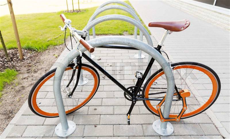 Transport, storage, security and safety concept - close up of fixed gear bicycle locked at street parking outdoors, stock photo