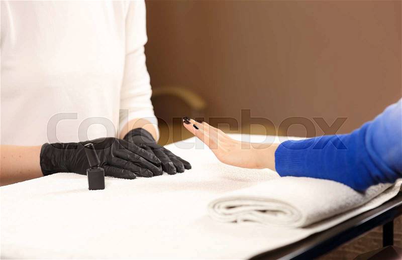 Finished customer manicure. Manicure master in black gloves does manicure, stock photo