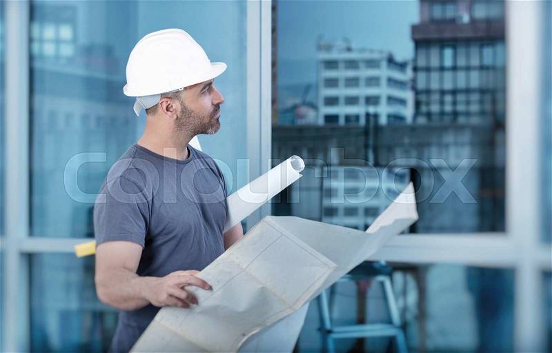 Portrait of an architect builder studying layout plan of the rooms, serious civil engineer working with documents on construction site, building and home renovation, professional foreman at work, stock photo
