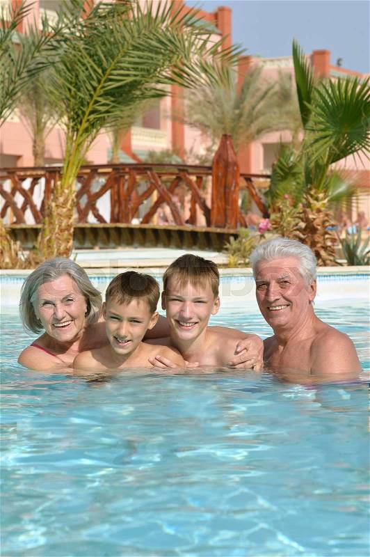 Happy Elderly couple resting at pool together with grandsons, stock photo