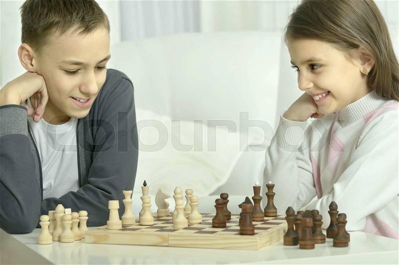 Little boy and little girl playing chess at home.Children playing chess, stock photo