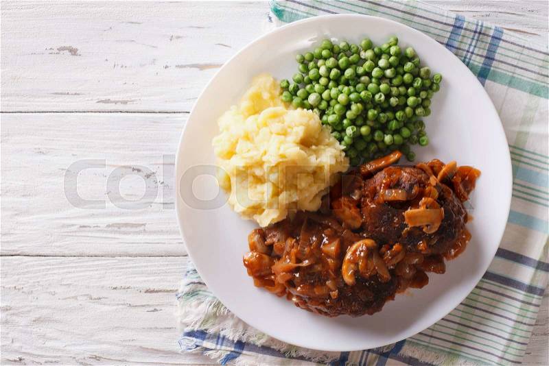 Salisbury steak with gravy, mashed potatoes and green peas close-up on a plate on the table. horizontal top view , stock photo