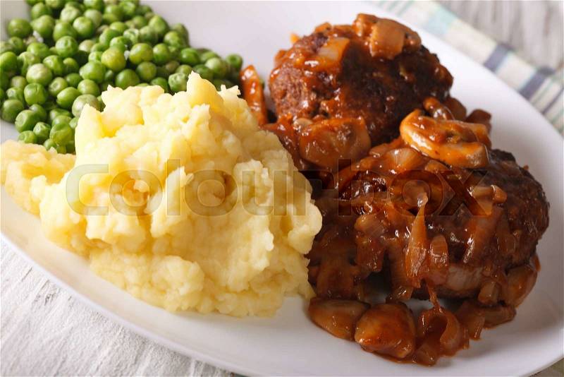 Salisbury steak with mashed potatoes and green peas close-up on a plate on the table. horizontal , stock photo