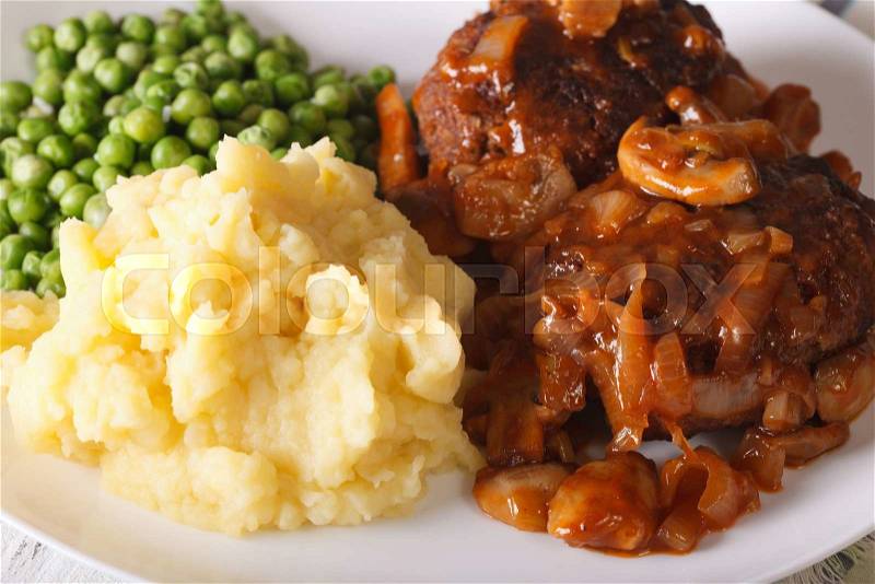 Salisbury steak with mushroom sauce, mashed potatoes and green peas close-up on a plate. horizontal , stock photo